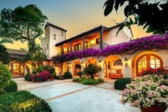 a large house with lots of flowers growing on the front and side of it's walls