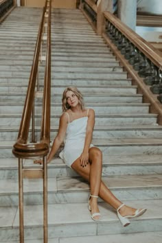 a woman is sitting on the stairs in a white dress