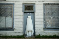 a wedding dress hanging in front of an old building