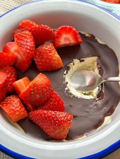 a bowl filled with chocolate and strawberries on top of a table