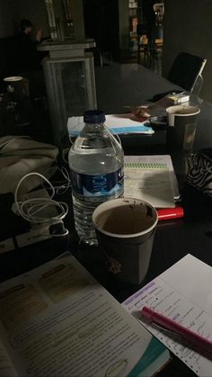 a desk with books, notebooks and a water bottle on it