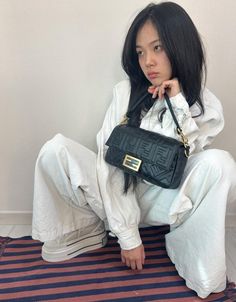 a woman sitting on the floor holding a black purse