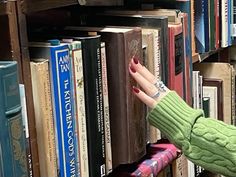 a hand reaching for a book on a bookshelf