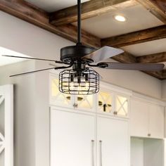 a ceiling fan that is hanging from the ceiling in a room with white walls and wooden beams