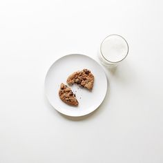 a white plate topped with two pieces of cookies next to a glass of milk on top of a table