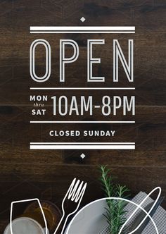 an open sign on a wooden table with plates and utensils