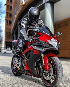 a man riding on the back of a red motorcycle