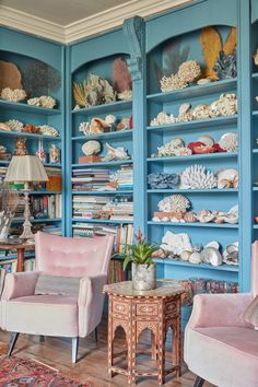 a living room filled with lots of blue bookshelves covered in corals and seashells