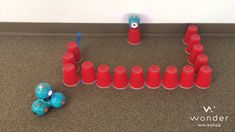 there is a toy elephant next to some red plastic cups on the floor, and an orange one in front of it