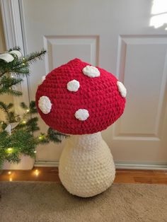 a crocheted mushroom sitting on top of a white vase next to a christmas tree