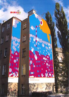 a tall building with a colorful mural on it's side in front of a blue sky