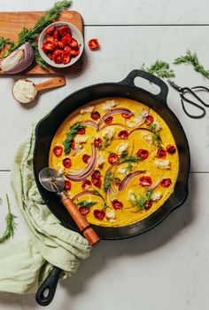 a skillet filled with food on top of a counter next to cutting boards and utensils