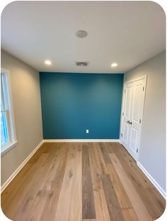 an empty room with blue walls and wood floors