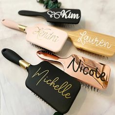 three personalized hair brushes sitting on top of a white table with black and gold combs