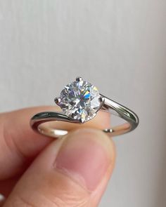 a person holding a ring with a diamond in it's middle and the other hand