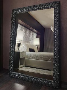 a bedroom with a large mirror on the wall and a bed in the reflection behind it