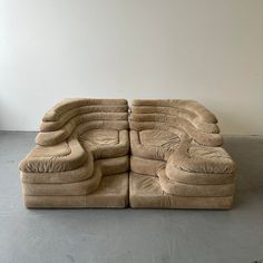 a large sectional couch sitting on top of a cement floor next to a white wall