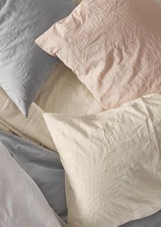 four pillows are laying on top of each other in different colors and sizes, along with one another