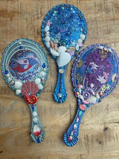 two decorative hair brushes sitting on top of a wooden table