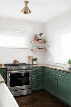 a kitchen with green cabinets and stainless steel stove top oven in the center, along with open shelving on the wall