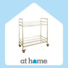 a gold serving cart with glass shelves on wheels and the words at home above it