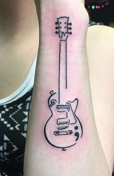 a woman's arm with a guitar tattoo on the left side of her wrist