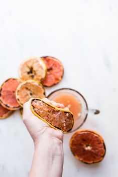 a person holding a hot dog bun with blood orange slices