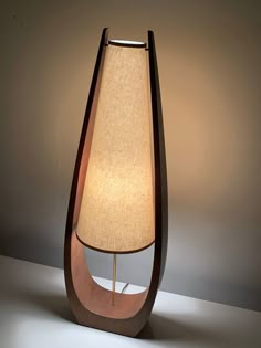 a lamp that is sitting on top of a table next to a light bulb in the shape of a cone