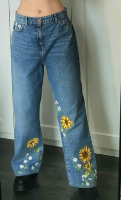 a woman wearing jeans with sunflowers painted on them