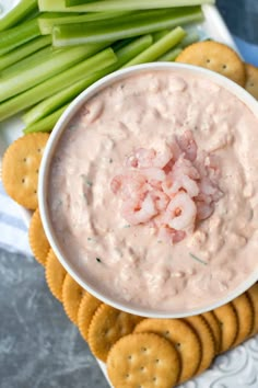 a bowl of dip surrounded by crackers and celery