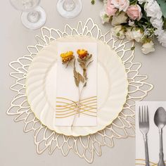 a place setting with flowers and silverware on the table for two people to eat