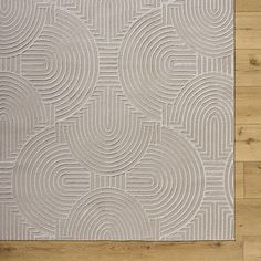 a white rug on top of a wooden floor next to a wall with wood floors