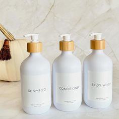 three bottles of shampoo next to a pumpkin on a marble countertop with a white pumpkin in the background