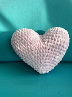 a pink crocheted heart sitting on top of a blue couch