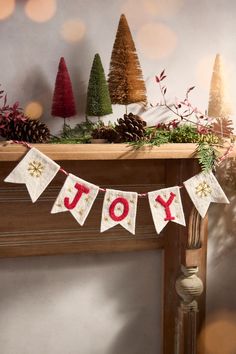 a christmas banner with the word joy hanging from it's side on a mantle