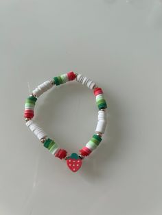 a bracelet made out of white, green and red beads with a heart on it