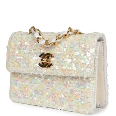 This Vintage micro half flap bag quilted iridescent ivory sequin and ribbed satin with gold hardware, features tonal stitching, cc turnlock closure, interwoven gold tone chain link and white canvas fabric crossbody/shoulder strap.The interior is lined in ribbed ivory satin fabric.Collection: 1-series (1989-1991)Origin: FranceCondition: Vintage; Excellent to Mint - This bag retains its shape and structure. The exterior shows some minor signs of wear with a few loose threads and sequins. The hardw Sparkly Designer Bags, White Chanel Bag, Fendi Purse, Vintage Chanel Bag, Vintage Designer Bags, Dream Bags, Vintage Chanel Handbags, Sequin Bag, Chanel Purse