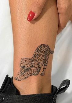 a woman's arm with a tattoo of a leopard on the left side of her leg