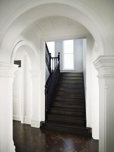 an entry way with wooden floors and white walls, along with black railings that lead up to the second floor