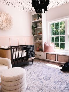 a baby's room with a crib, chair, and bookshelf