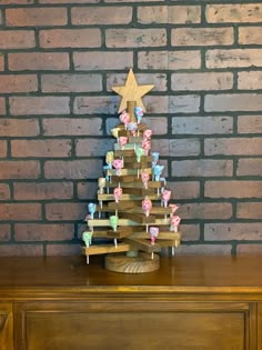 a small wooden christmas tree on top of a brown dresser next to a brick wall