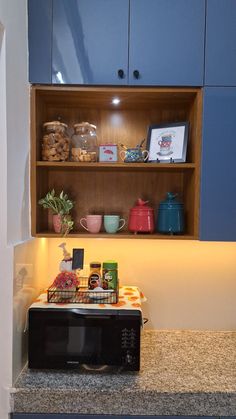 a microwave oven sitting on top of a counter next to a shelf filled with food