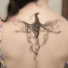 the back of a woman's neck with a bird tattoo on it