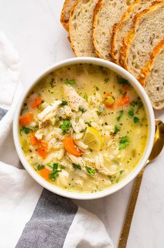 a bowl of chicken noodle soup next to slices of bread on a white and blue towel