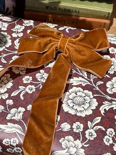 a gift wrapped in brown velvet with a bow sitting on top of a table next to books