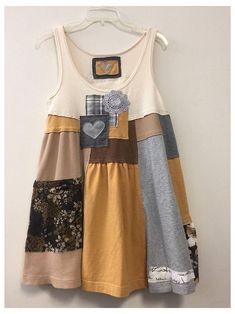 a dress hanging on a wall with different colors and shapes in the front, including an applique heart