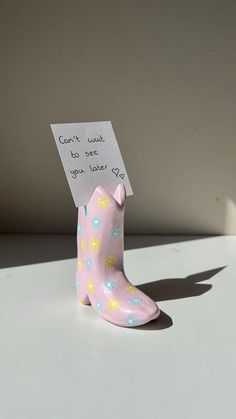 a small pink boot with a note attached to it