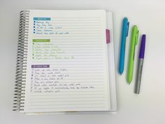 a notebook with writing on it next to two markers and a pen, all lined up in different colors