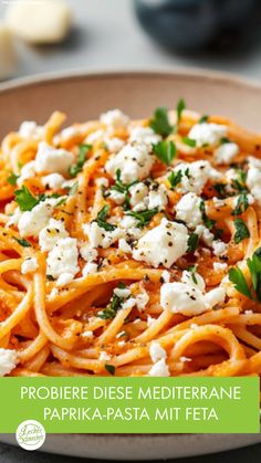 a plate of pasta with feta cheese and parsley on top, sitting on a table