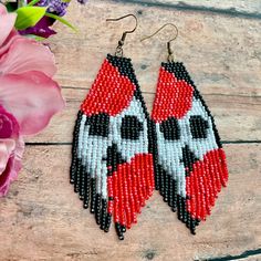 two pairs of beaded earrings sitting on top of a wooden table next to flowers